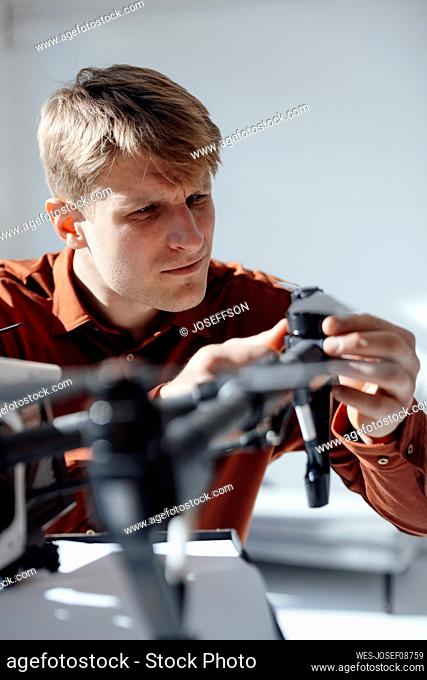 Businessman examining drone at desk in office