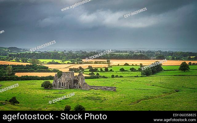 Old ruins of Hore Abbey surrounded by fields and forest, dark dramatic storm sky. Located next to Rock of Cashel castle, County Tipperary, Ireland