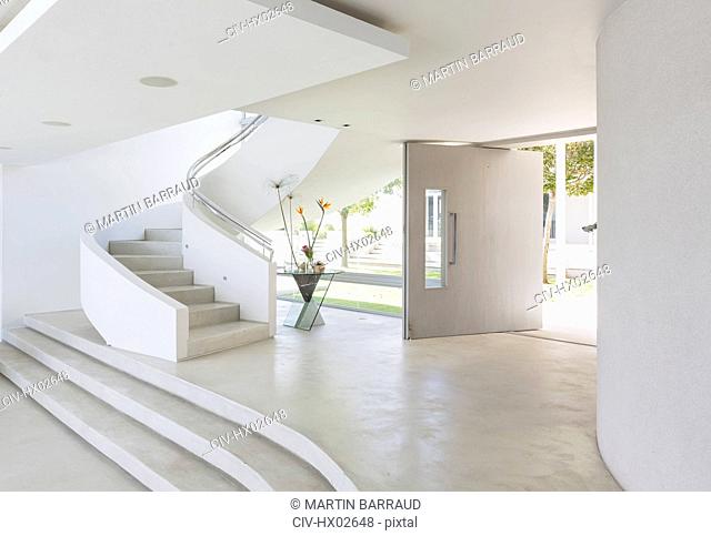 White foyer and spiral staircase in modern luxury home showcase interior