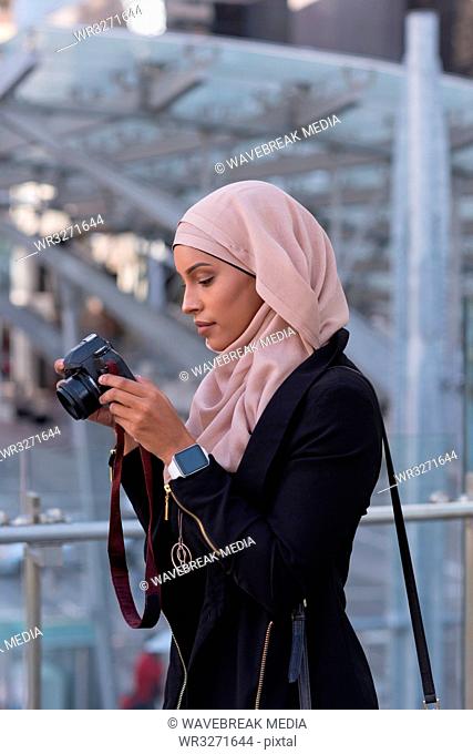 Woman reviewing photos in digital camera at balcony