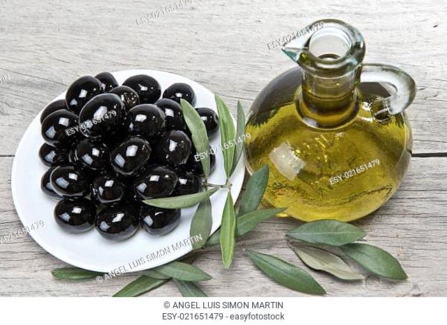 Olive oil and a plate with black olives