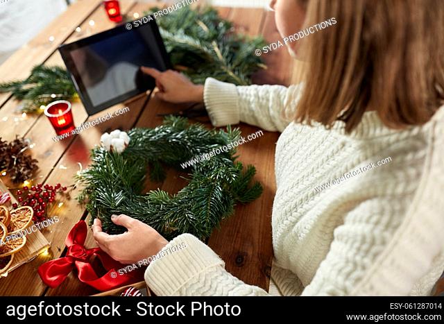 woman with tablet pc makes christmas wreath