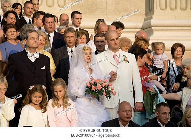 Bride and groom with wedding guests pose for photographs on steps of Saint Stephens Basilica after service