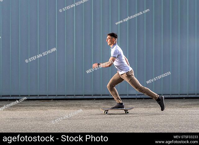 Young man skateboarding in front of wall