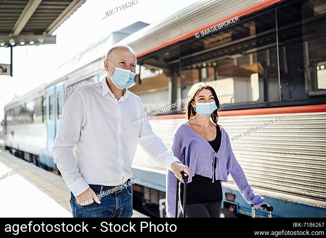 Tourists with suitcases and masks on the platform next to the train, Portugal, Europe