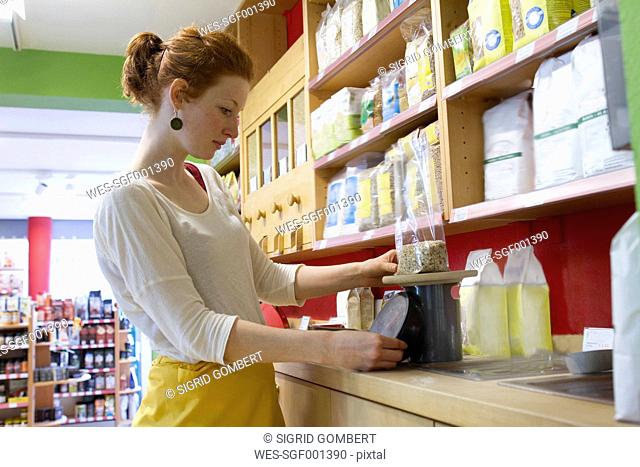 Young woman in wholefood shop weighing granola