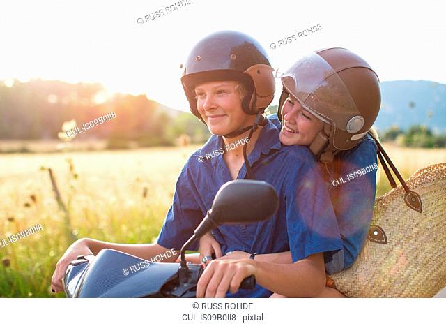 Romantic young couple riding moped on rural road, Majorca, Spain