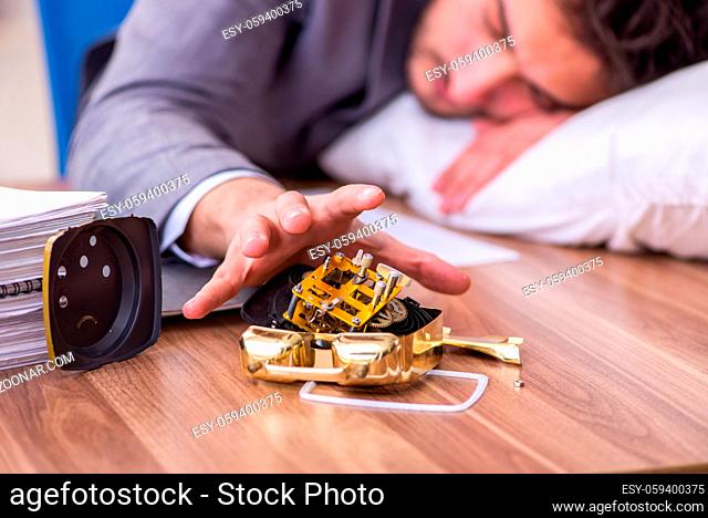 Young businessman employee in oversleeping concept