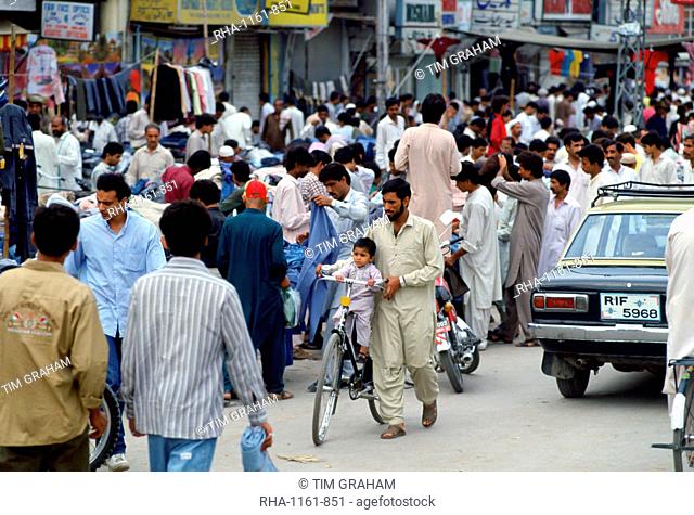 Man wheeling child on bicycle in crowded street in Islamabad in Pakistan