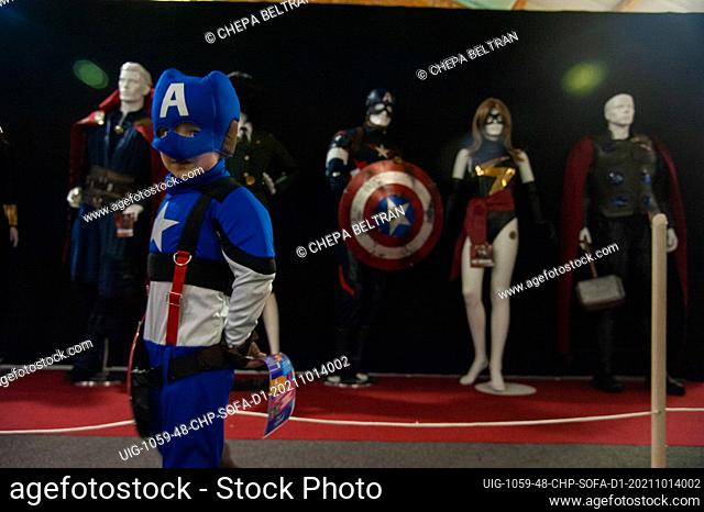 A child poses for a photo in front of a set of the Marvel Avengers costumes during the first day of the SOFA (Salon del Ocio y la Fantasia) 2021