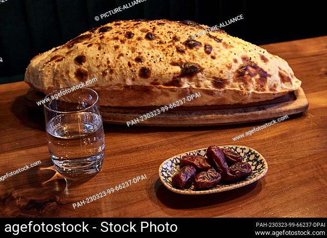 23 March 2023, Hamburg: A glass of water, a bowl of dates and the Sisme Ekmek stone-baked bread are on the table at the Pamukkale Köz restaurant
