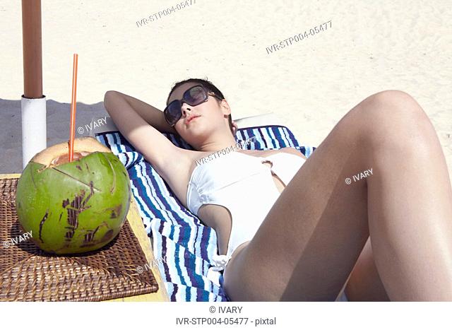 A young woman relaxing on a deck chair on the beach