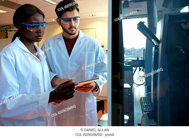 Young female and male scientists looking at scientific equipment in laboratory