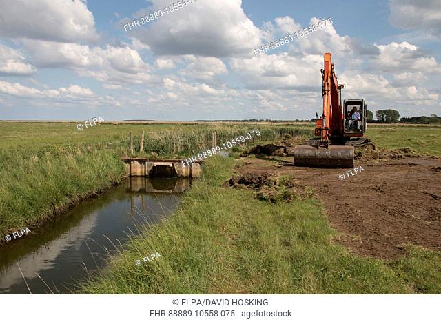 Using a digger for maintenance work on sluice gate at Deepdale Marsh north Norfolk