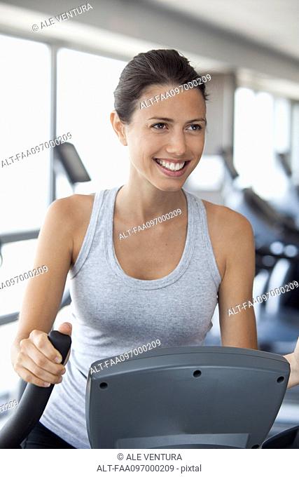 Young woman using step climber at gym