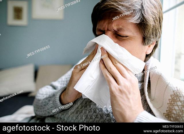 Sick man blowing nose at home