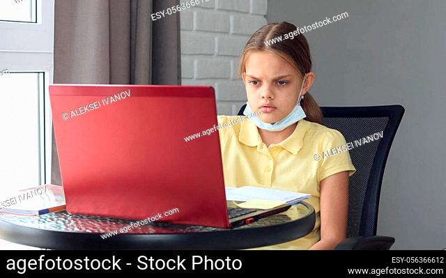 Girl in self-isolation mode sits at a computer and does homework online