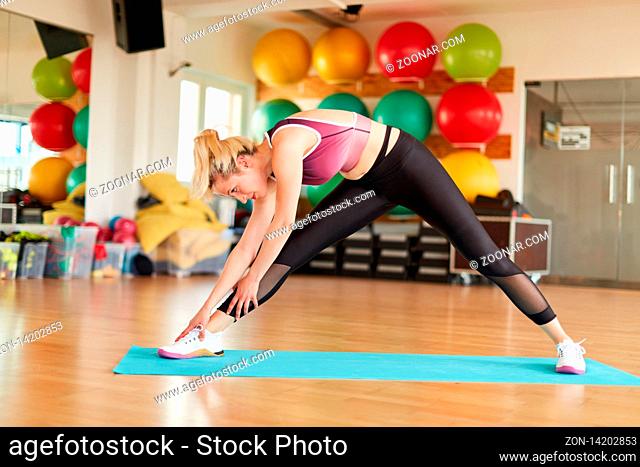 Junge Frau macht eine Stretching Übung zum Aufwärmen im Fitnesscenter