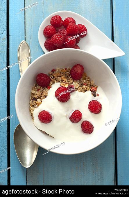 Bowl of muesli with raspberries on wooden table, close up