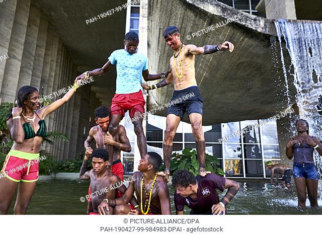 26 April 2019, Brazil, Brasilia: Young Indians play in a well in front of the Justice Department in the water, waiting for the minister to meet their leaders