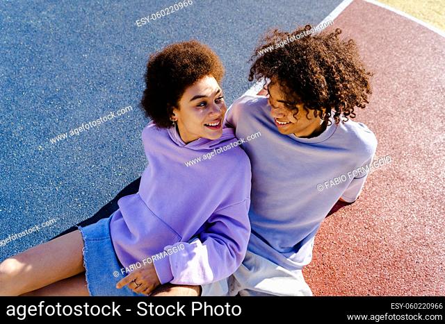 Interracial young couple dating outdoors, colored and modern urban background - Multiethnic people with stylish and cool urban clothes bonding outdoors