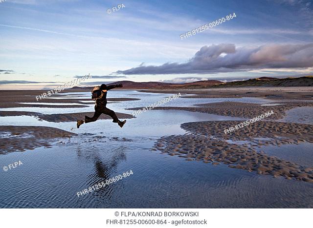 Man jumping over tidal sea puddles, Killinalan Point, Loch Gruinart, Isle of Islay, Inner Hebrides, Scotland