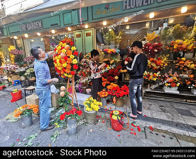 26 February 2023, Vietnam, Hanoi: Vietnamese working on various flower arrangements in front of a flower store on a street in the Old Quarter