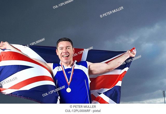 athlete cheering with U.K. flag and medal