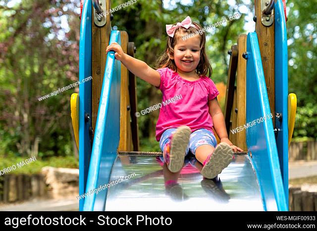 Portrait of smiling little girl on playground slide