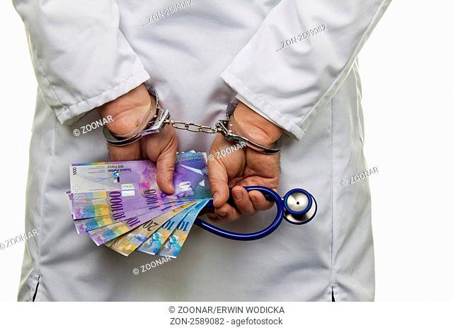 Ein Arzt mit Schweizer Franken Geldscheinen und Handschellen