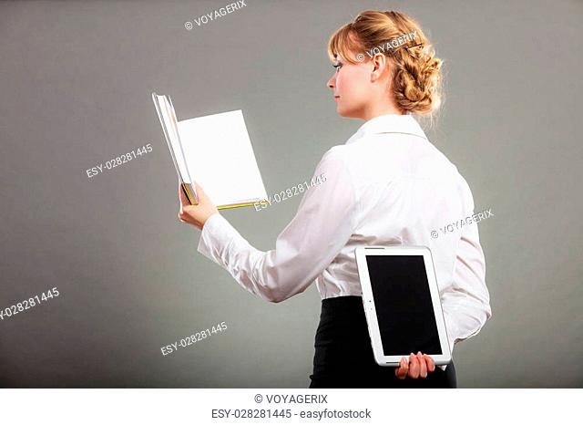 Woman learning with book holding ebook reader behind back. Choice between modern educational technology and traditional way method