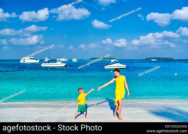 Three year old toddler boy on beach with mother. Summer family vacation at Maldives