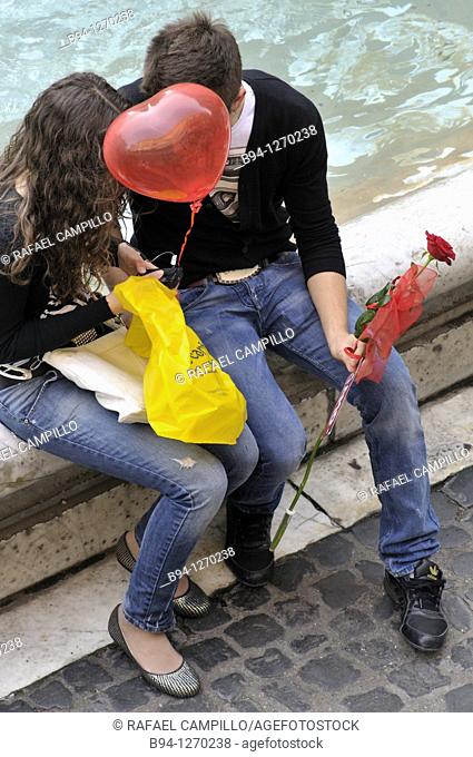 Couple in love with red balloon in the shape of heart and a red rose. Trevi Fountain. Rome, Italy