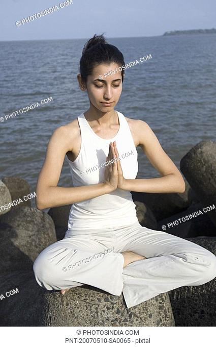 Young woman doing yoga on a rock