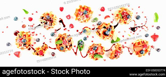 Belgian waffles with fresh fruit, chocolate, and mint, overhead flat lay shot on a white background