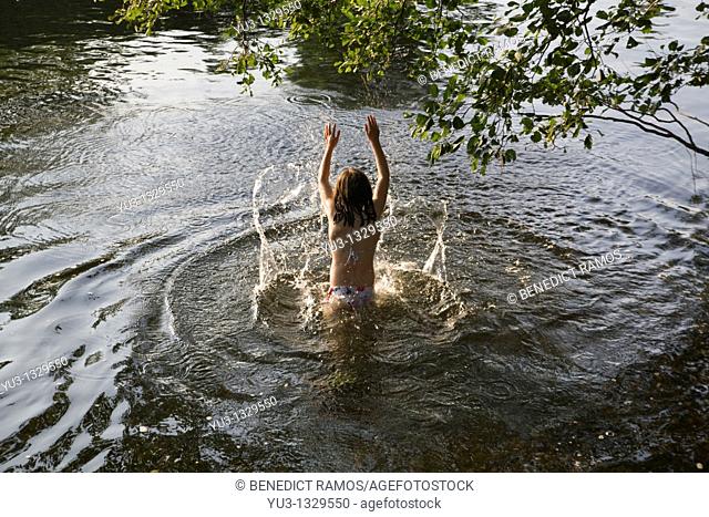 Young girl in a river splashing water