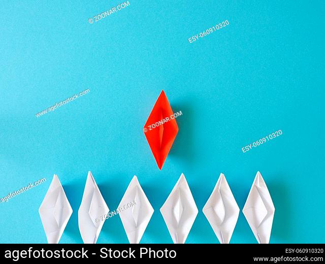 Leadership or Teamwork business concept with paper boat on a blue paper background with space for text