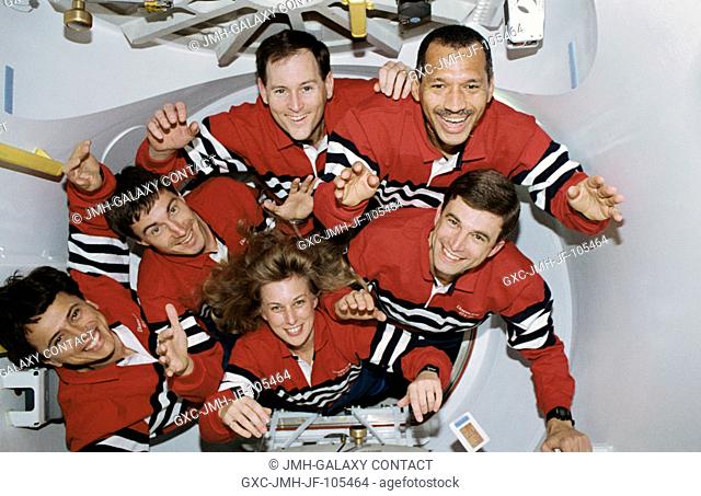 Five NASA astronauts and a Russian cosmonaut squeeze through the tunnel which connects the shirt-sleeve environments of the space shuttle Discovery and the...