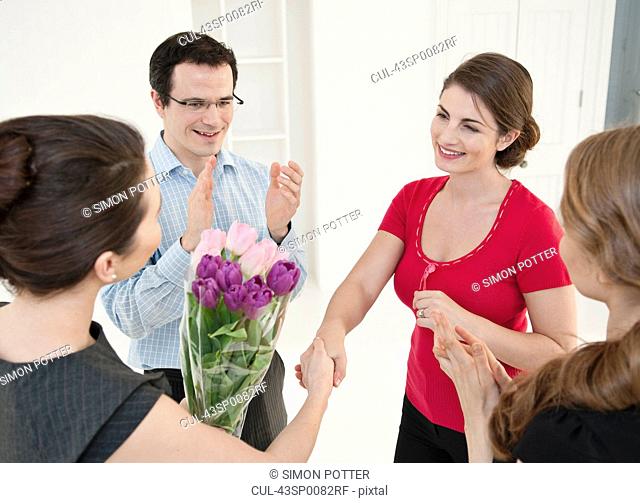 Business people giving colleague flowers