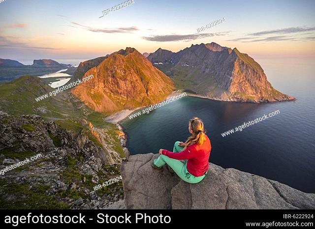 Evening atmosphere, hiker on top of Ryten, sea, Kvalvika beach and mountains, Fredvang, Lofoten, Nordland, Norway, Europe