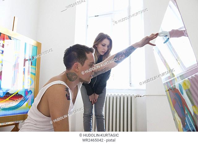 Painter and girlfriend in studio looking at canvas