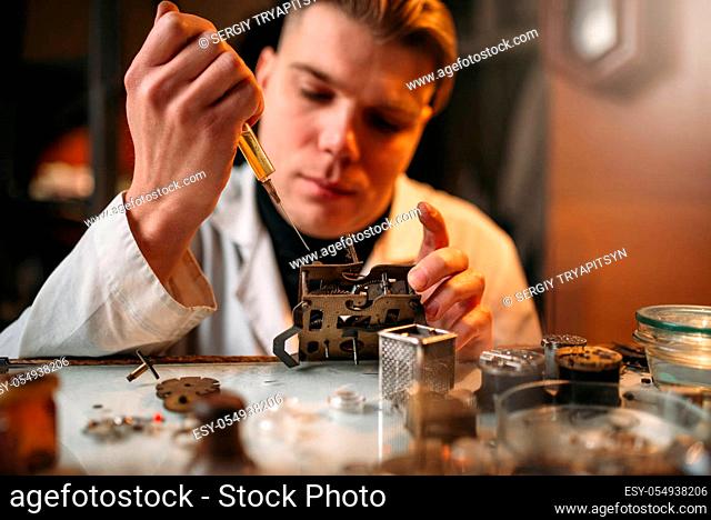 Watchmaker oil lubricates the mechanism of the old clock. Mechanical watch repairing
