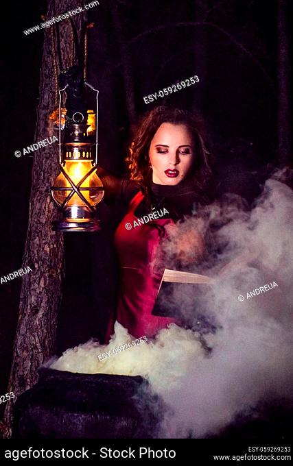 girl alone at night in the forest brews a potion and wonders for marriage, surrounded by candles and smoke
