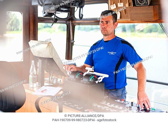 01 July 2019, Lower Saxony, Neu Darchau: Ferryman Gerd Westedt steers the Elbe ferry ""Tanja"". It's only a few hundred meters