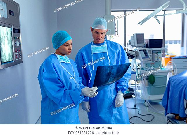 Surgeons discussing over x ray report in operating room at hospital
