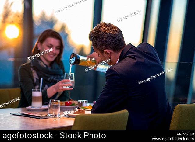 young happy loving couple enjoying romantic dinner while celebrating Valentines day near the window at luxury restaurant