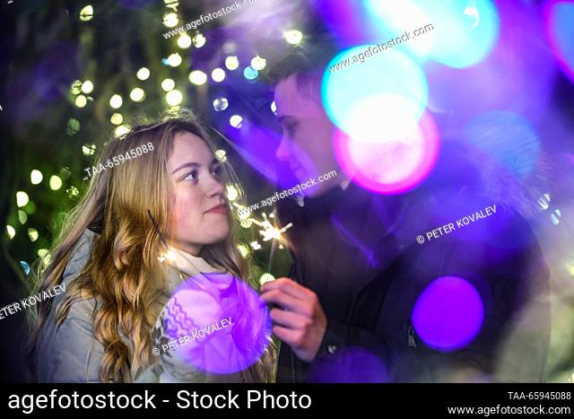 RUSSIA, ST PETERSBURG - DECEMBER 20, 2023: A young couple enjoy Bengal lights during a ceremony to light up the main Christmas tree of St Petersburg in Palace...