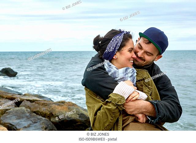 Young couple hugging on rocky beach