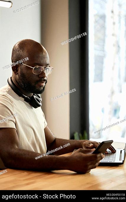 Young man with eyeglasses using smart phone on table at home