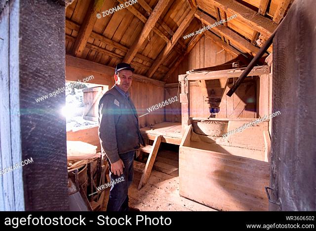 portrait of a miller in retro wooden watermill with old equipment